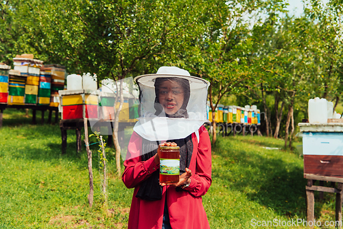 Image of Portrait of Arab investitor in the beekeeping department of a honey farm holding a jar of honey in her hand