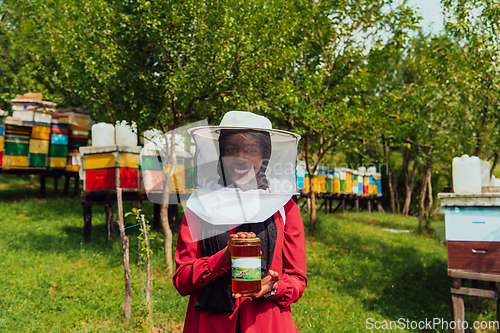 Image of Portrait of Arab investitor in the beekeeping department of a honey farm holding a jar of honey in her hand