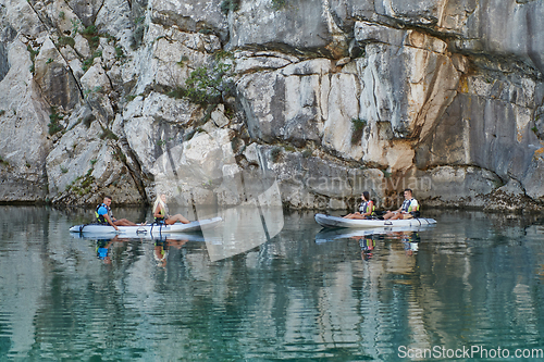 Image of A group of friends enjoying having fun and kayaking while exploring the calm river, surrounding forest and large natural river canyons