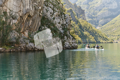 Image of A group of friends enjoying having fun and kayaking while exploring the calm river, surrounding forest and large natural river canyons