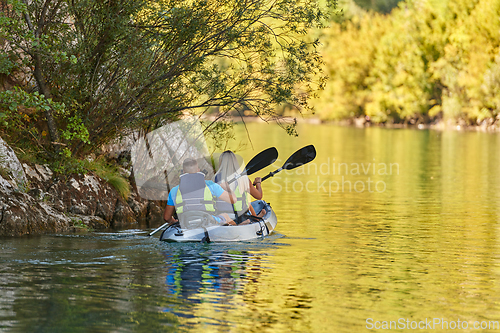 Image of A young couple enjoying an idyllic kayak ride in the middle of a beautiful river surrounded by forest greenery