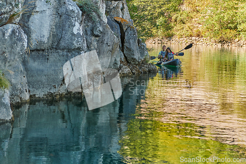 Image of A young couple enjoying an idyllic kayak ride in the middle of a beautiful river surrounded by forest greenery