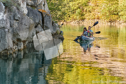 Image of A young couple enjoying an idyllic kayak ride in the middle of a beautiful river surrounded by forest greenery