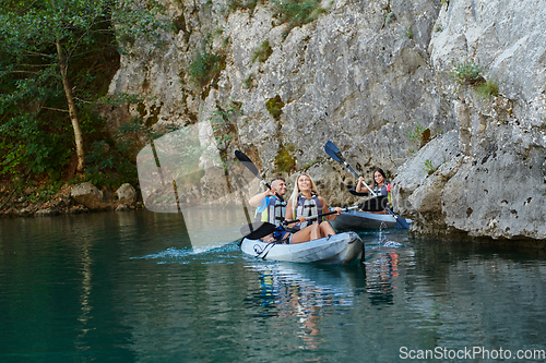 Image of A group of friends enjoying having fun and kayaking while exploring the calm river, surrounding forest and large natural river canyons