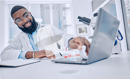 Image of Wiping keyboard, research and a scientist or man in a lab, working and disinfectant for a laptop. Happy, healthcare and a doctor or an employee cleaning a computer of a virus for medical safety