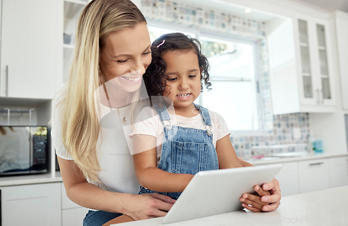 Image of Blended family, adoption and a mother with her daughter on a tablet in the kitchen for education or study. Children, diversity and learning with woman teaching her girl kid in their home together