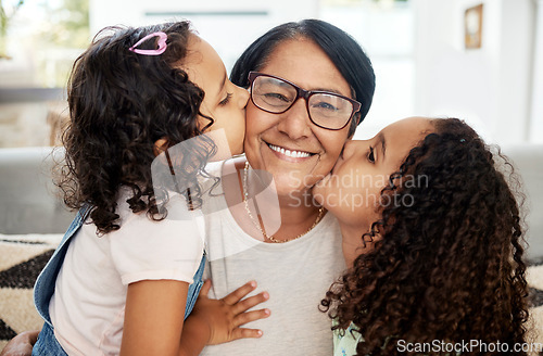 Image of Children kissing their grandmother on her cheek with love, care and happiness in the living room. Happy, smile and portrait of senior woman hugging her girl kids in the lounge of the family home.