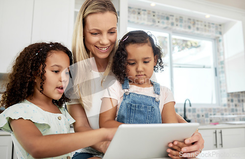 Image of Blended family, adoption and a mother with her kids on a tablet in the kitchen for education or learning. Sister, diversity and study with woman teaching her girl daughters in their home together