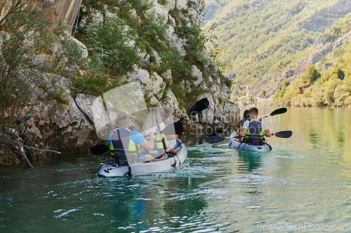 Image of A group of friends enjoying having fun and kayaking while exploring the calm river, surrounding forest and large natural river canyons