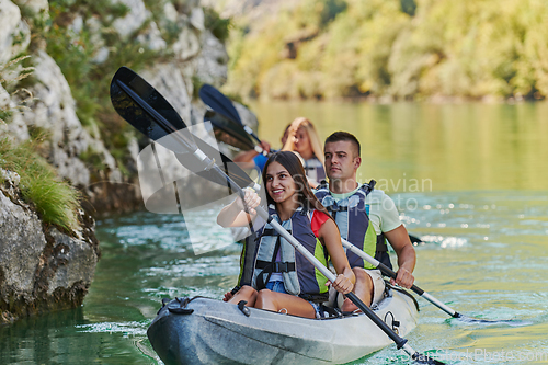 Image of A group of friends enjoying having fun and kayaking while exploring the calm river, surrounding forest and large natural river canyons