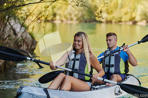 Image of A young couple enjoying an idyllic kayak ride in the middle of a beautiful river surrounded by forest greenery