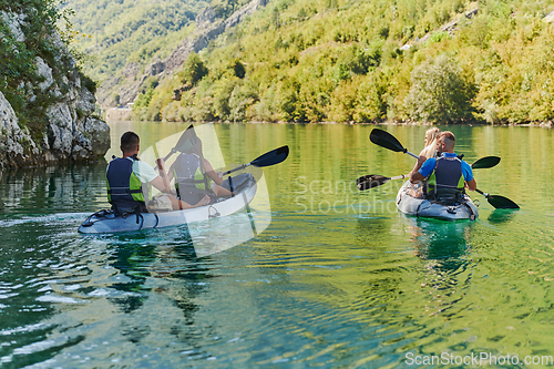 Image of A group of friends enjoying having fun and kayaking while exploring the calm river, surrounding forest and large natural river canyons