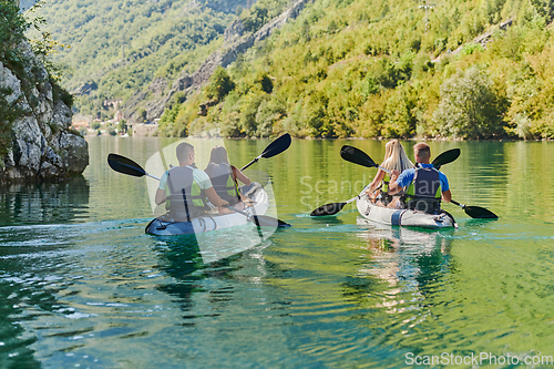 Image of A group of friends enjoying having fun and kayaking while exploring the calm river, surrounding forest and large natural river canyons