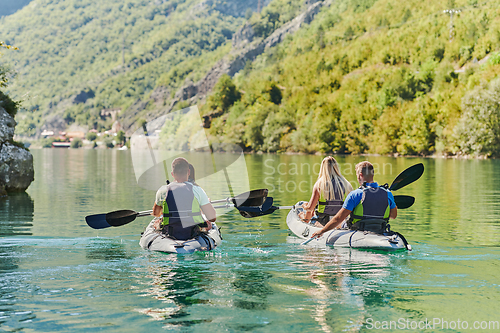 Image of A group of friends enjoying having fun and kayaking while exploring the calm river, surrounding forest and large natural river canyons