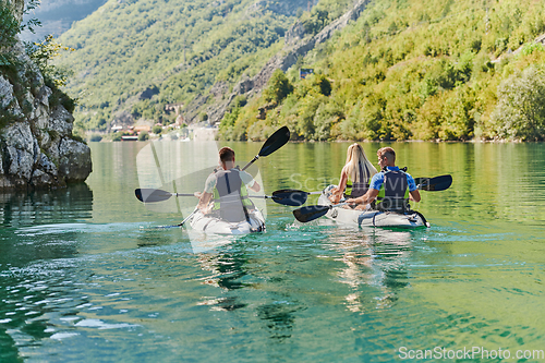 Image of A group of friends enjoying having fun and kayaking while exploring the calm river, surrounding forest and large natural river canyons