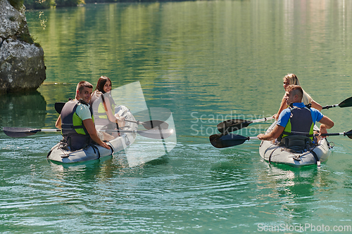 Image of A group of friends enjoying having fun and kayaking while exploring the calm river, surrounding forest and large natural river canyons