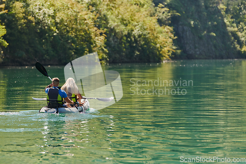 Image of A young couple enjoying an idyllic kayak ride in the middle of a beautiful river surrounded by forest greenery