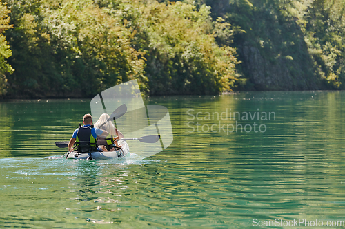 Image of A young couple enjoying an idyllic kayak ride in the middle of a beautiful river surrounded by forest greenery