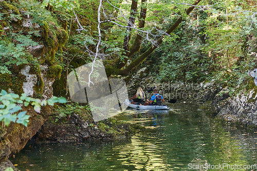 Image of A young couple enjoying an idyllic kayak ride in the middle of a beautiful river surrounded by forest greenery