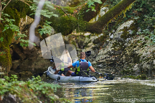 Image of A young couple enjoying an idyllic kayak ride in the middle of a beautiful river surrounded by forest greenery