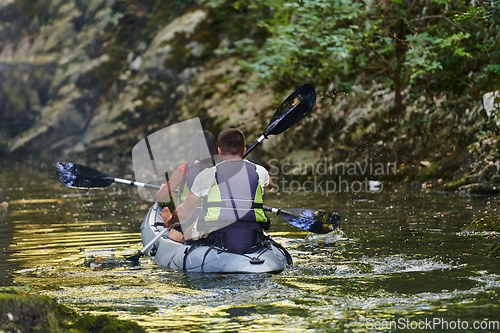 Image of A young couple enjoying an idyllic kayak ride in the middle of a beautiful river surrounded by forest greenery