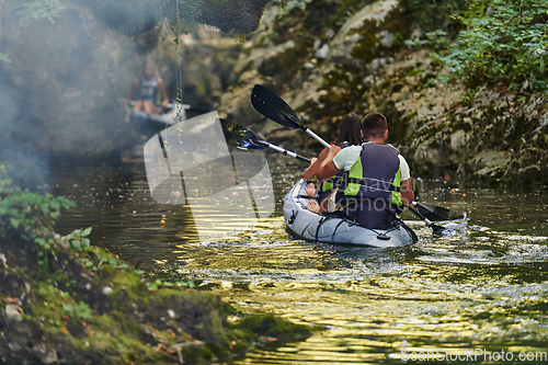 Image of A group of friends enjoying having fun and kayaking while exploring the calm river, surrounding forest and large natural river canyons