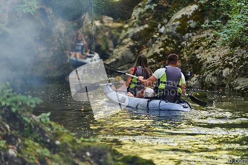 Image of A group of friends enjoying having fun and kayaking while exploring the calm river, surrounding forest and large natural river canyons