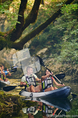 Image of A group of friends enjoying having fun and kayaking while exploring the calm river, surrounding forest and large natural river canyons