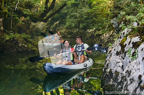 Image of A group of friends enjoying having fun and kayaking while exploring the calm river, surrounding forest and large natural river canyons