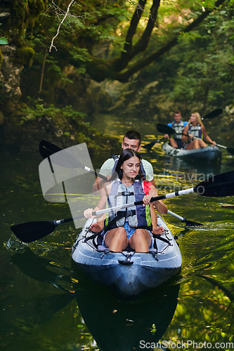 Image of A group of friends enjoying having fun and kayaking while exploring the calm river, surrounding forest and large natural river canyons