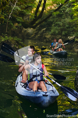 Image of A group of friends enjoying having fun and kayaking while exploring the calm river, surrounding forest and large natural river canyons