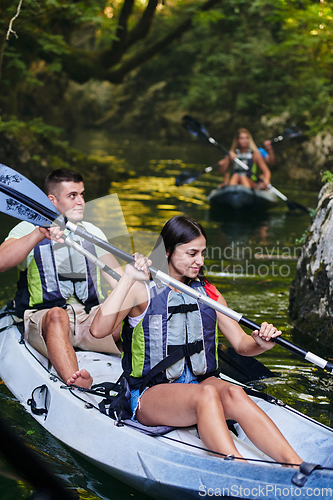 Image of A group of friends enjoying having fun and kayaking while exploring the calm river, surrounding forest and large natural river canyons