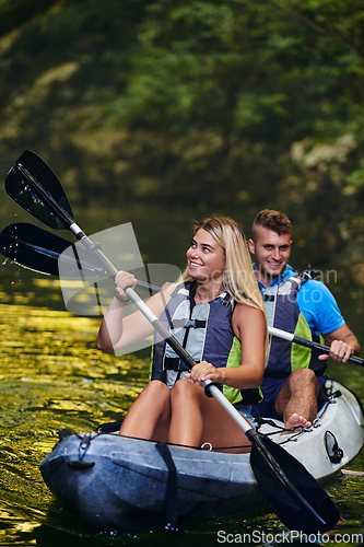 Image of A young couple enjoying an idyllic kayak ride in the middle of a beautiful river surrounded by forest greenery