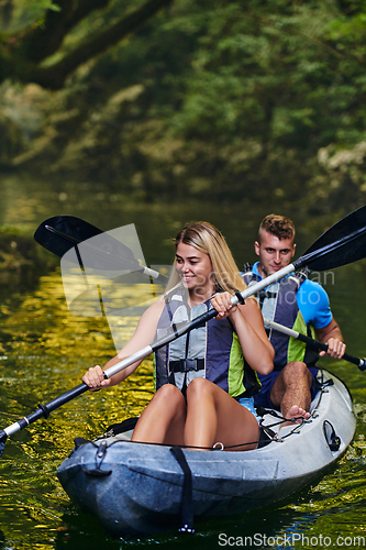 Image of A young couple enjoying an idyllic kayak ride in the middle of a beautiful river surrounded by forest greenery