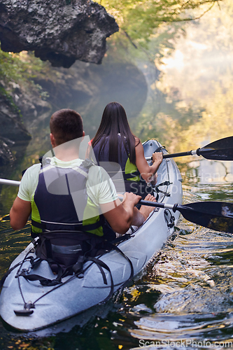 Image of A young couple enjoying an idyllic kayak ride in the middle of a beautiful river surrounded by forest greenery