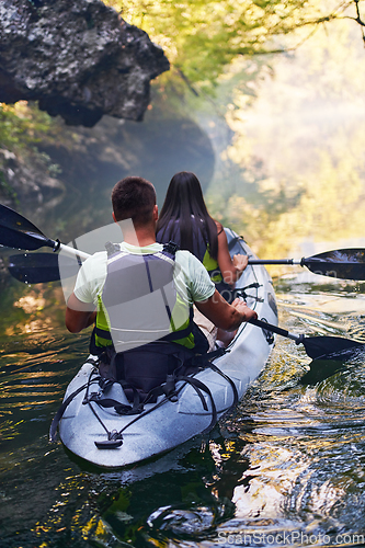 Image of A young couple enjoying an idyllic kayak ride in the middle of a beautiful river surrounded by forest greenery