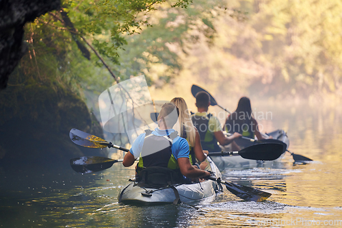 Image of A group of friends enjoying having fun and kayaking while exploring the calm river, surrounding forest and large natural river canyons