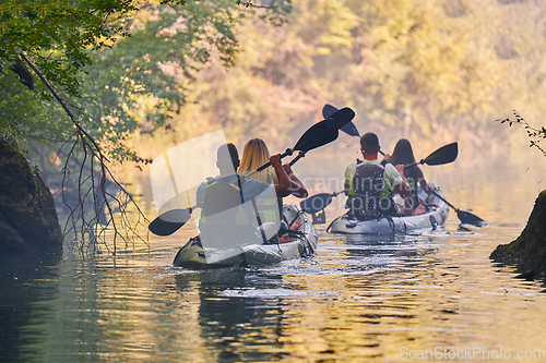 Image of A group of friends enjoying having fun and kayaking while exploring the calm river, surrounding forest and large natural river canyons