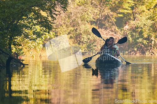 Image of A group of friends enjoying having fun and kayaking while exploring the calm river, surrounding forest and large natural river canyons