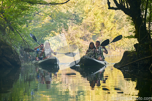 Image of A group of friends enjoying having fun and kayaking while exploring the calm river, surrounding forest and large natural river canyons