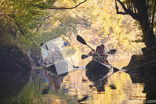 Image of A group of friends enjoying having fun and kayaking while exploring the calm river, surrounding forest and large natural river canyons