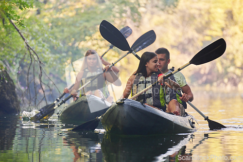 Image of A group of friends enjoying having fun and kayaking while exploring the calm river, surrounding forest and large natural river canyons