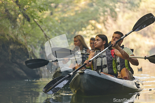 Image of A group of friends enjoying having fun and kayaking while exploring the calm river, surrounding forest and large natural river canyons