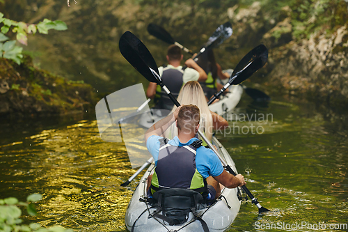 Image of A group of friends enjoying having fun and kayaking while exploring the calm river, surrounding forest and large natural river canyons