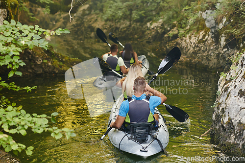 Image of A group of friends enjoying having fun and kayaking while exploring the calm river, surrounding forest and large natural river canyons