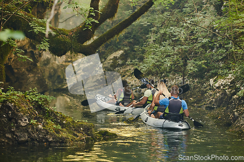 Image of A group of friends enjoying having fun and kayaking while exploring the calm river, surrounding forest and large natural river canyons