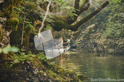 Image of A group of friends enjoying having fun and kayaking while exploring the calm river, surrounding forest and large natural river canyons