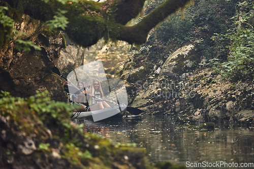 Image of A group of friends enjoying having fun and kayaking while exploring the calm river, surrounding forest and large natural river canyons