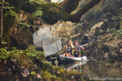 Image of A group of friends enjoying having fun and kayaking while exploring the calm river, surrounding forest and large natural river canyons