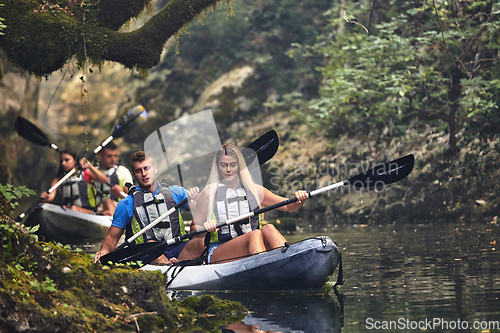 Image of A group of friends enjoying having fun and kayaking while exploring the calm river, surrounding forest and large natural river canyons